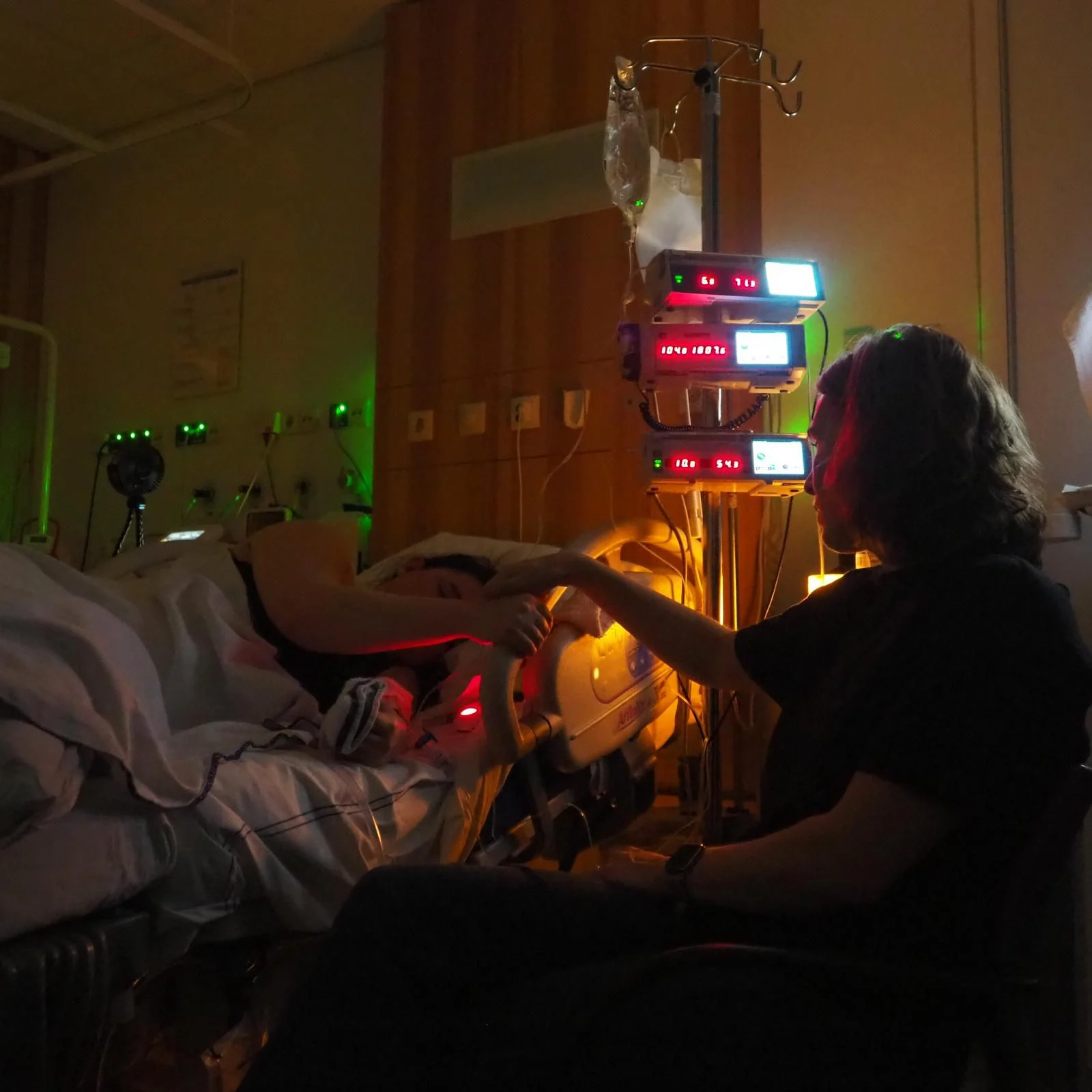Doula Iris keeping watch at night beside the bed of a woman in labour in hospital
