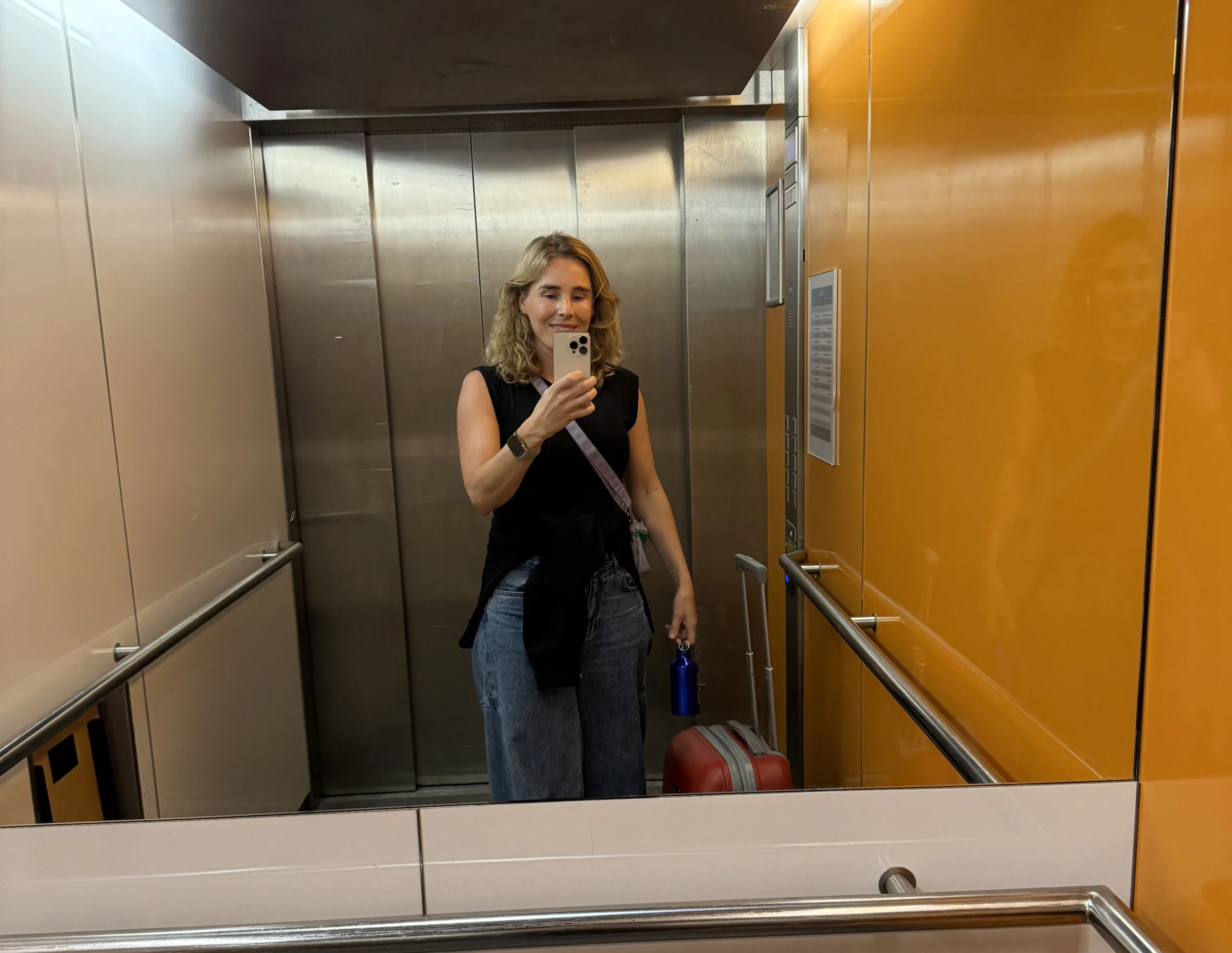 Doula Iris in a lift with a red suitcase, on her way to a birth